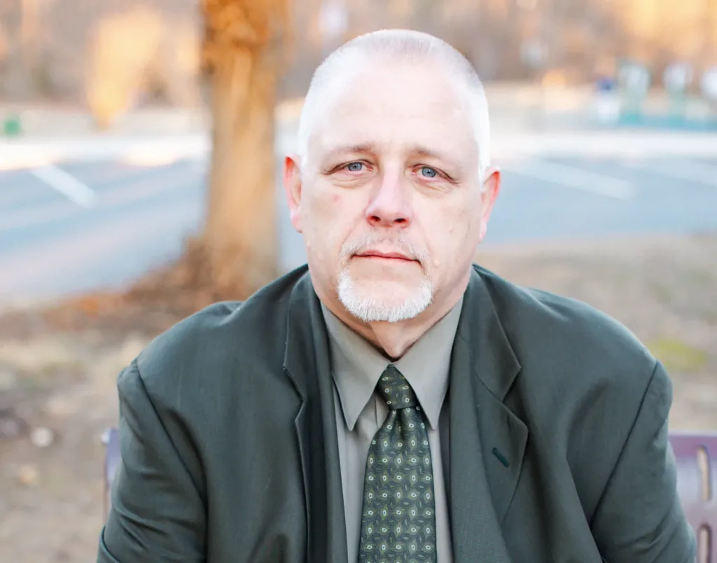 A man in a green suit sitting on a park bench.