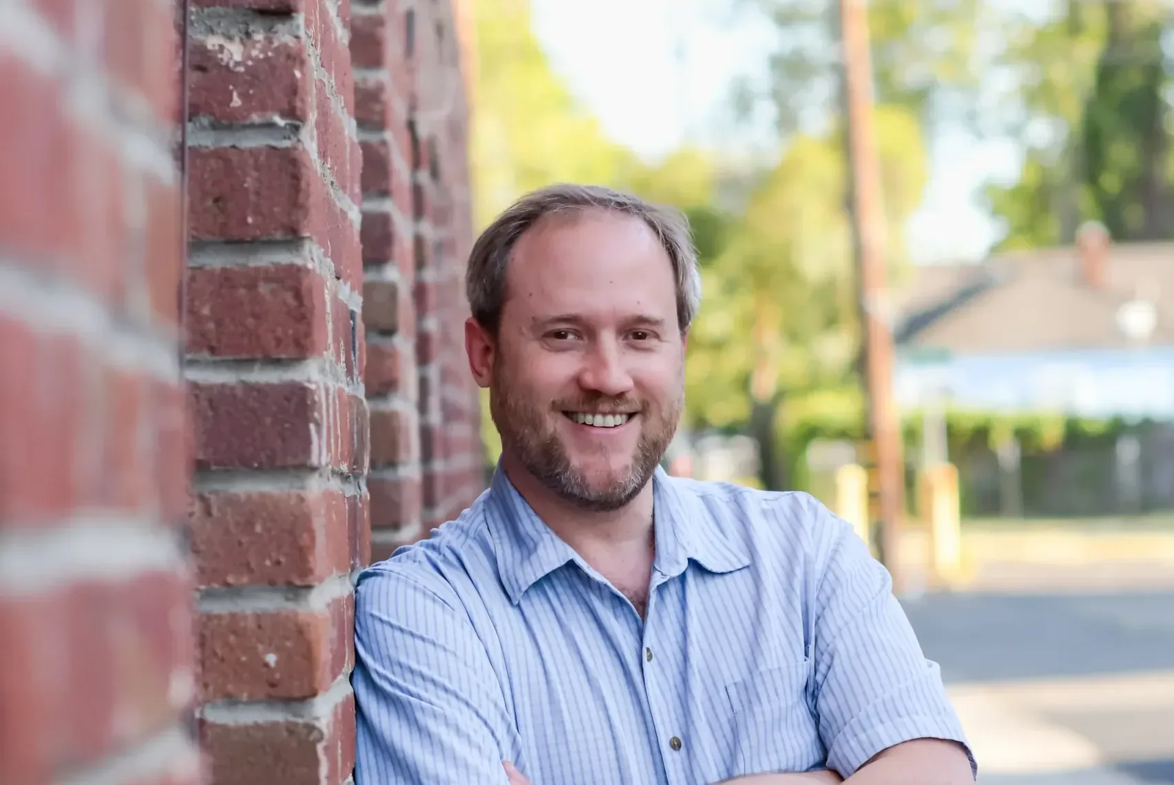 Isaac Newman, plaintiff in Newman v. EGEA, smiling as he leans against a brick wall.