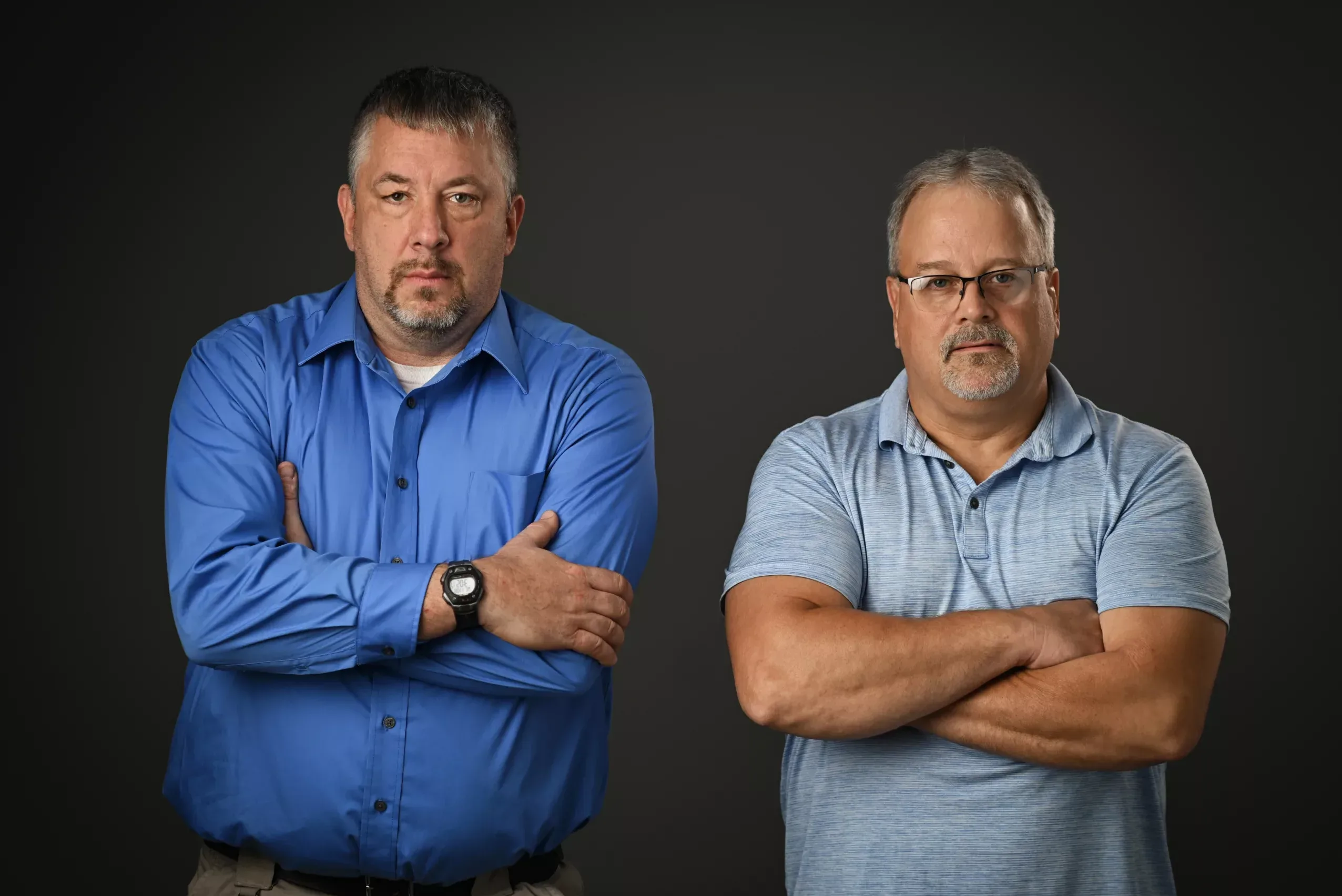 Yedlosky-30 Chris Taylor and Cory Yedlosky, plaintiffs in Taylor v. PSCOA and Yedlosky v. PSCOA, standing with their arms crossed in front of a black background.