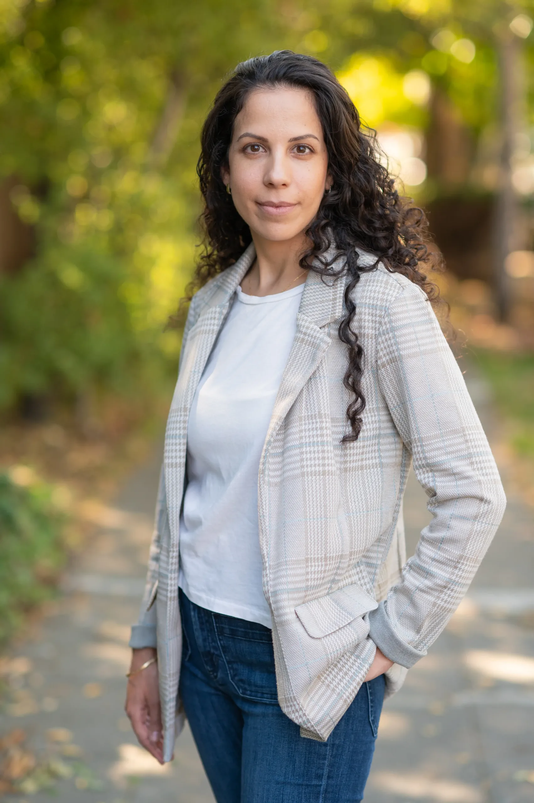 karin-yaniv-headshot-side Full body shot of client Karin Yaniv, an Israeli postdoc at UC Berkeley suing her union for anti-Semitism, smiling under a tree-lined street.