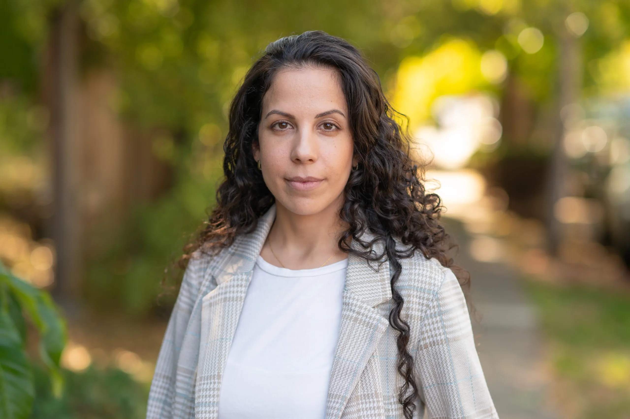 Our client Karin Yaniv, an Israeli postdoc at UC Berkeley suing her union for anti-Semitism, smiling under a tree-lined street.