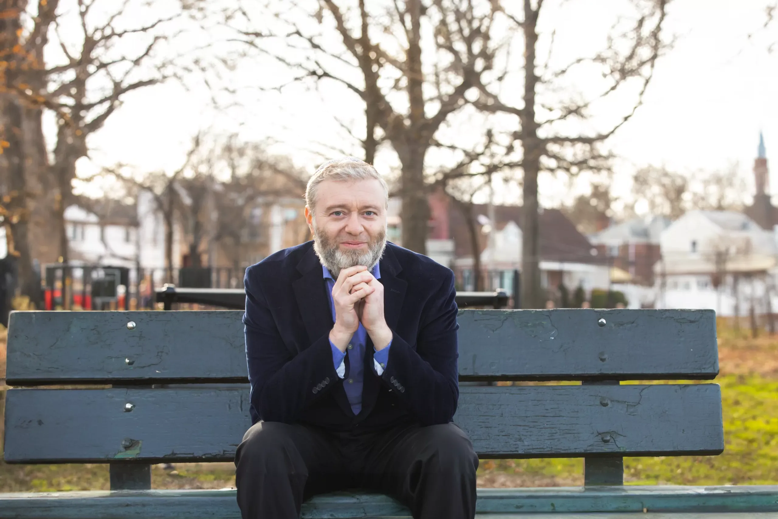 Avraham Goldstein, lead plaintiff in Goldstein v. PSC/CUNY, sitting on a park bench and resting his chin on his folded hands.