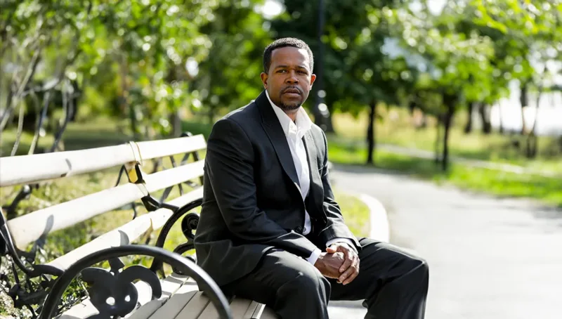 Ed Seabron, plaintiff in Seabron v. AFSCME, D.C. 37, sitting on a park bench next to a paved pathway.