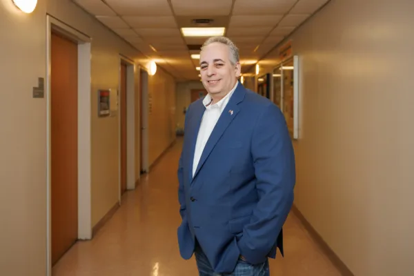 Jeff Lax, plaintiff in Goldstein v. PSC/CUNY, standing in a classroom-lined hallway at CUNY.
