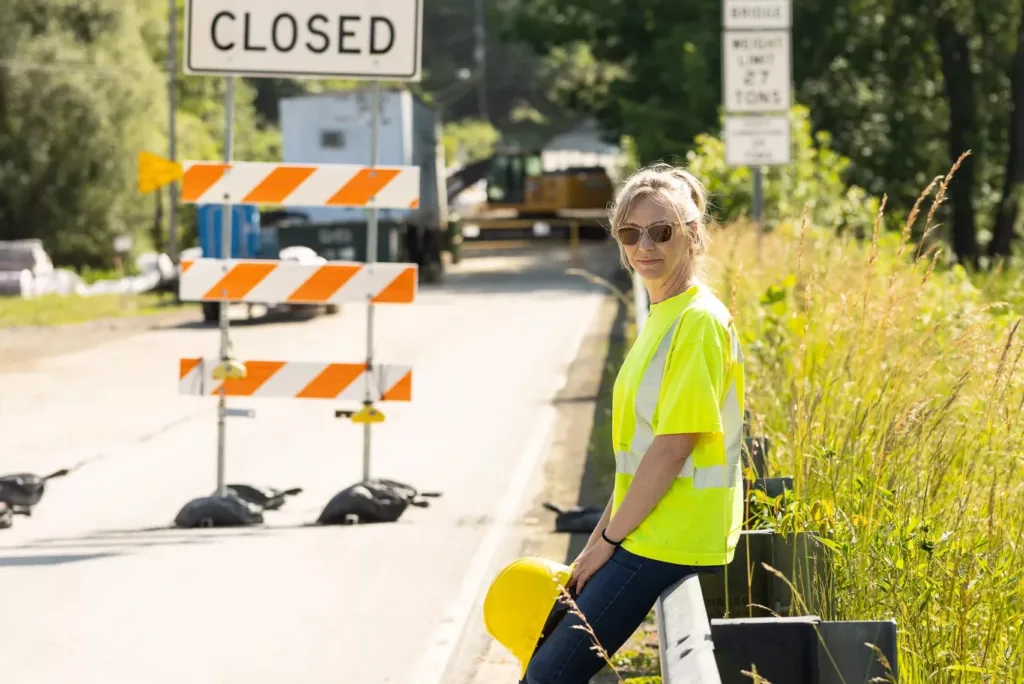 Mindy McFetridge, plaintiff in McFetridge v. AFSCME, Council 13, sitting on a guardrail in front of road construction.