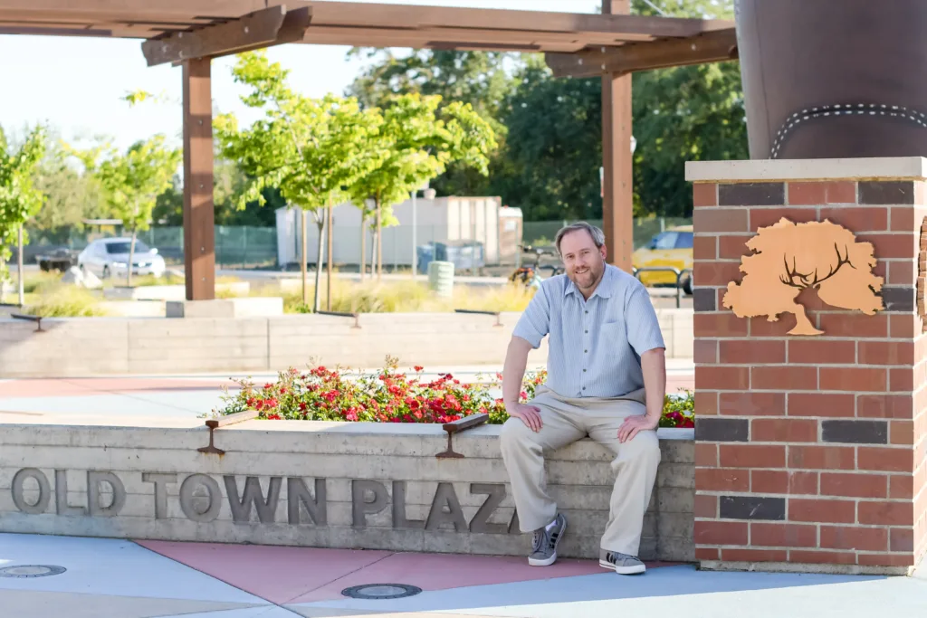 Isaac Newman, plaintiff in Newman v. EGEA, sitting on an Old Town Plaza sign in Elk Grove, California.