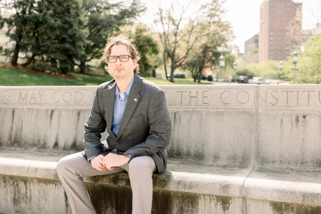 A man sitting on a stone bench in front of trees